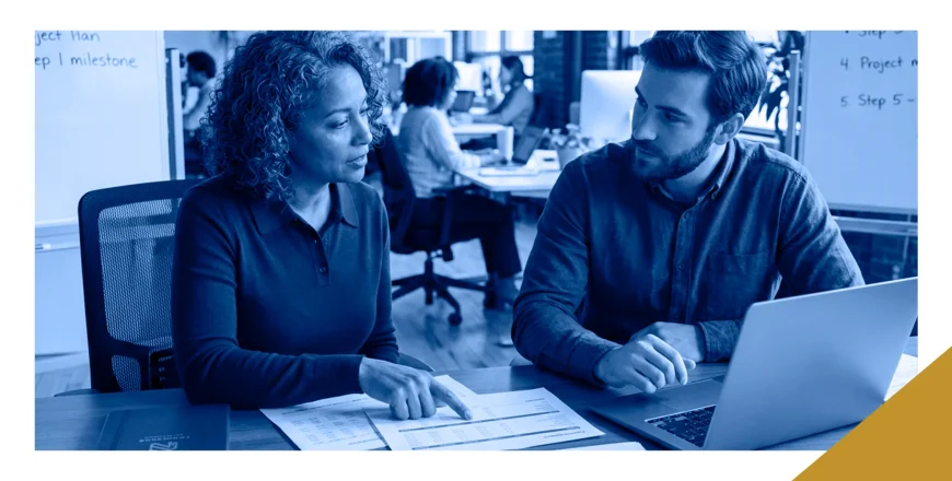 A fractional CFO reviewing financial reports with a business leader at a laptop in an open office